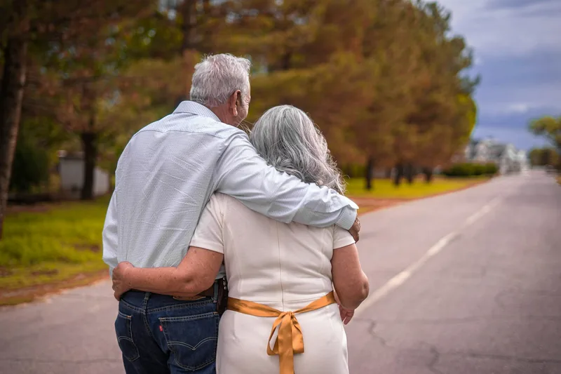 Pareja mayor abrazada caminando por una calle