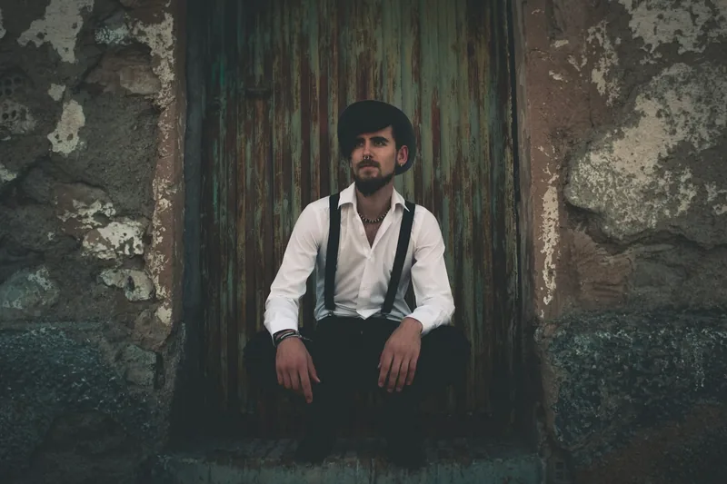 Hombre sentado frente a una puerta antigua